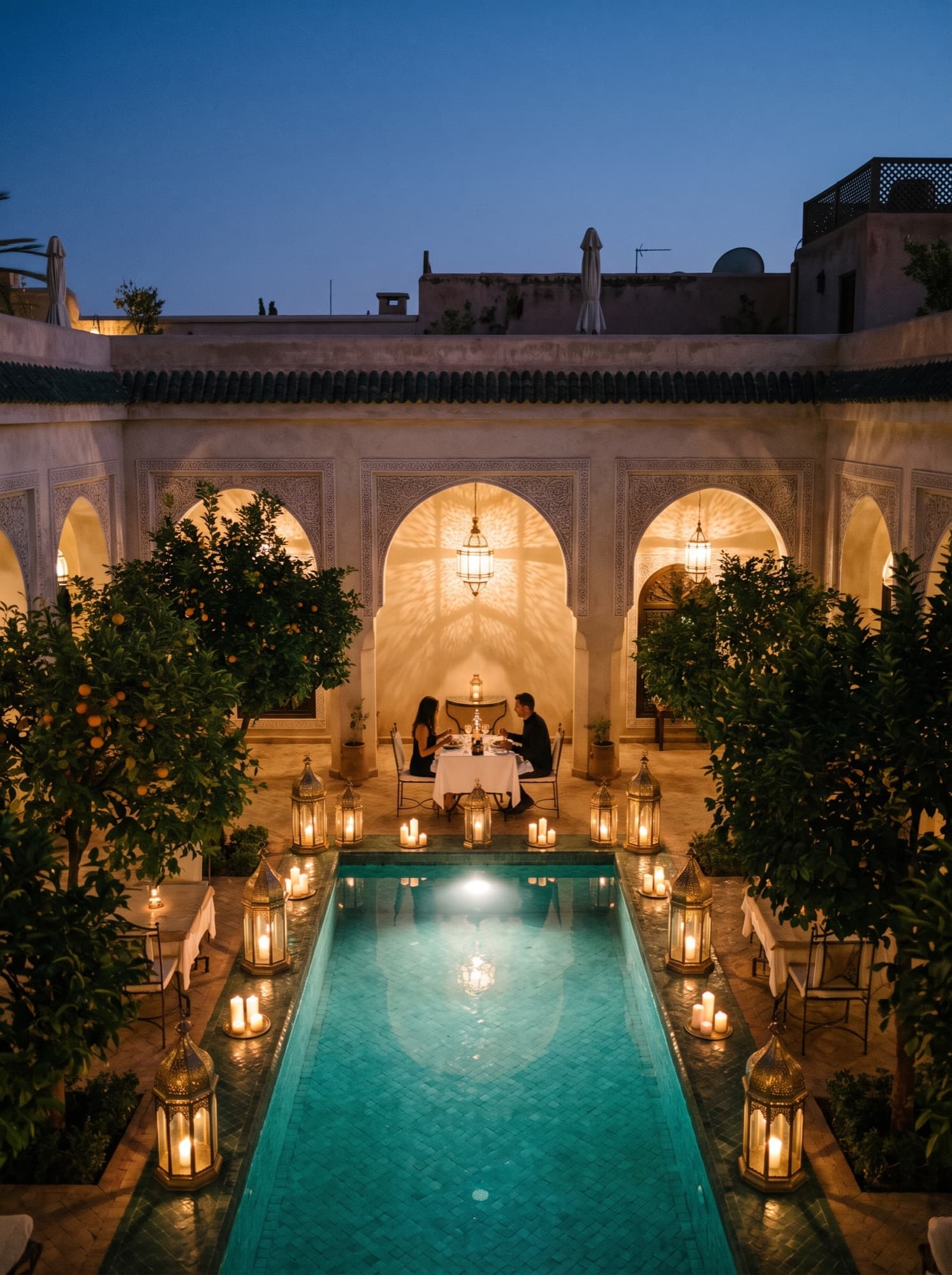 Cour d'un riad à Marrakech à l'heure bleue, lanternes et piscine, un couple à table
